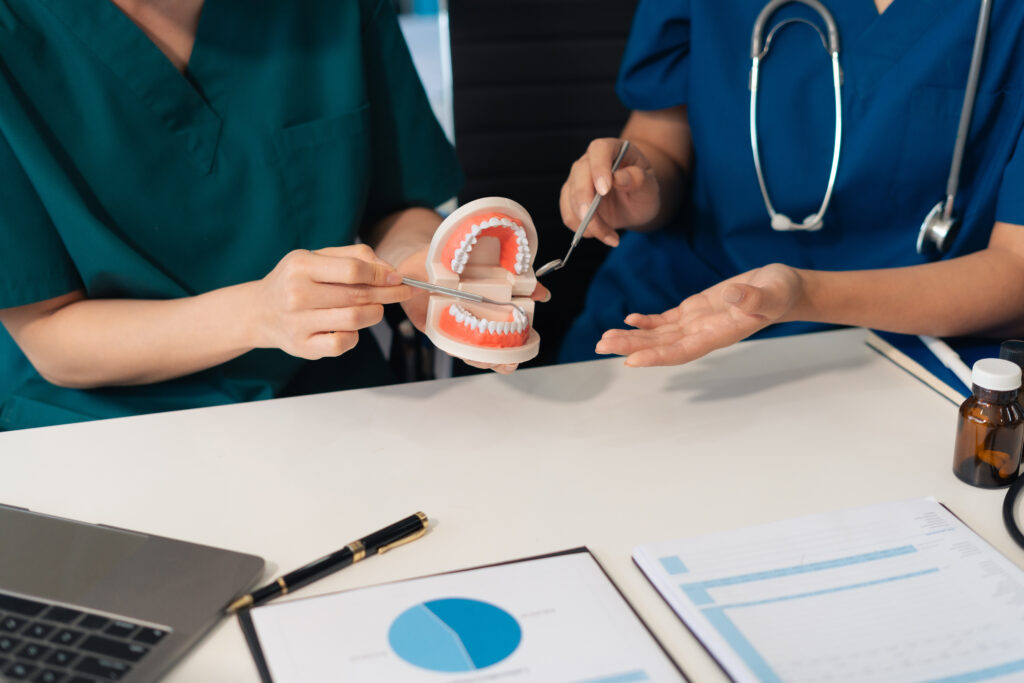 Dentists reviewing treatment plans with tooth models and holistic dental resources for patient education